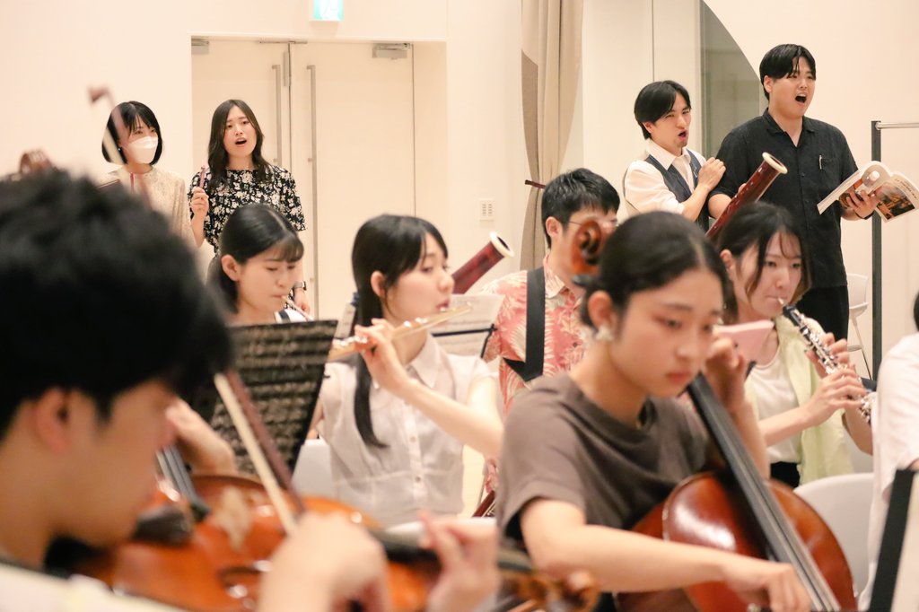 オーケストラの向こう側で稽古に励む歌手たち