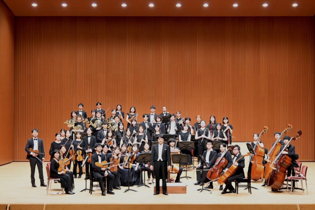中心に立つ指揮者濱本広洋を囲んで舞台上で撮られた集合写真