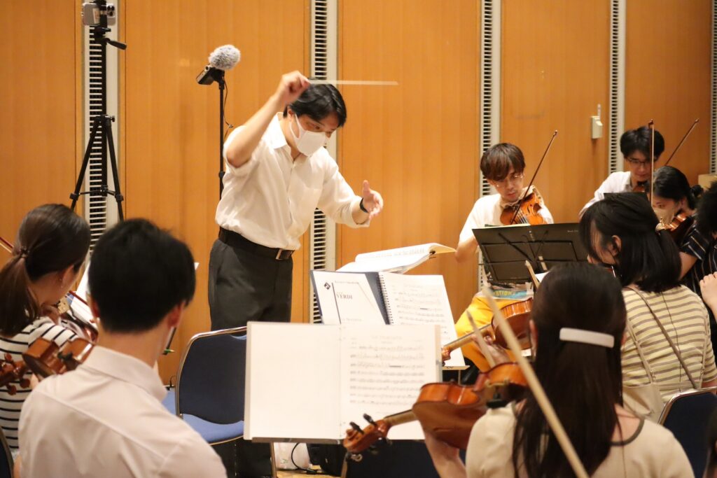 稽古でオーケストラの指揮を振る指揮者濱本広洋の写真